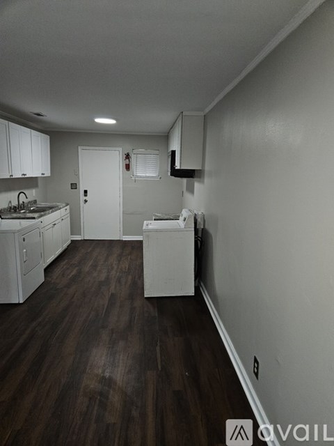 A kitchen with white appliances and wooden floors.
