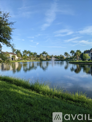 A calm lake surrounded by greenery and trees under a clear blue sky.