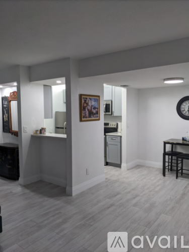 A room with a wooden floor and a white wall with a clock on it.