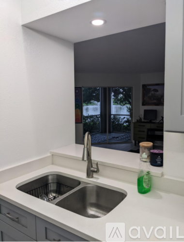 A kitchen sink with a green bottle on the counter.