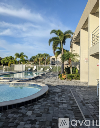 A pool area with a tiled floor and palm trees in the background.