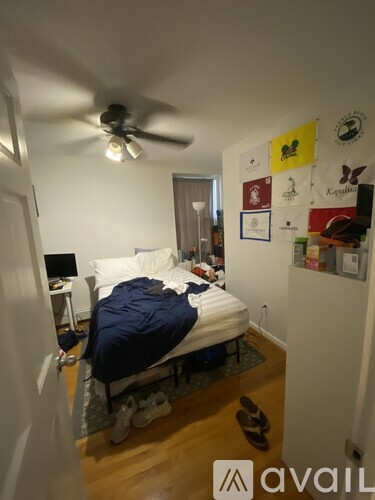 A bedroom with a bed, a ceiling fan, and pictures on the wall.