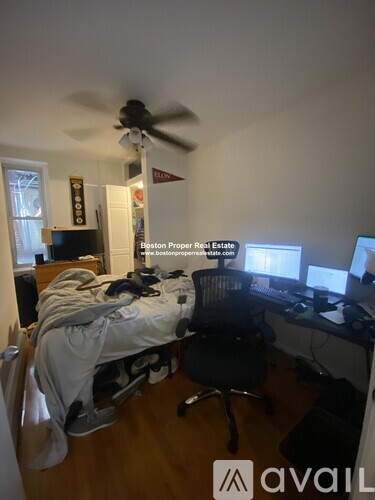 A room with a bed, desk, and a ceiling fan.