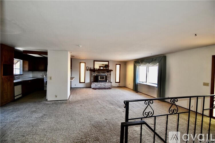 A spacious living room with a fireplace and a balcony.