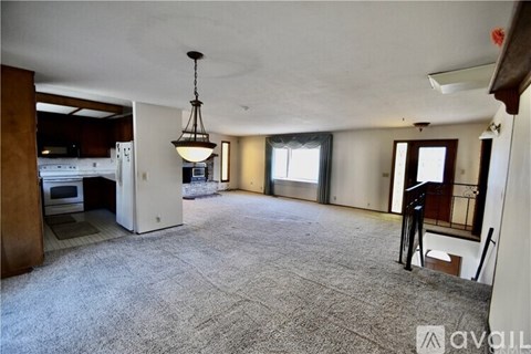 A large, empty living room with a kitchen area in the background.