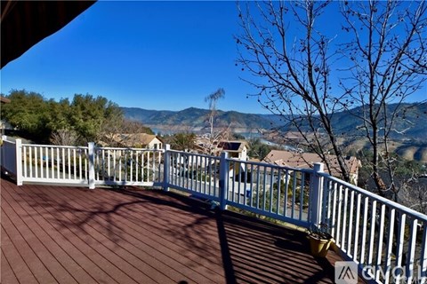 A deck with a white railing overlooks a valley.