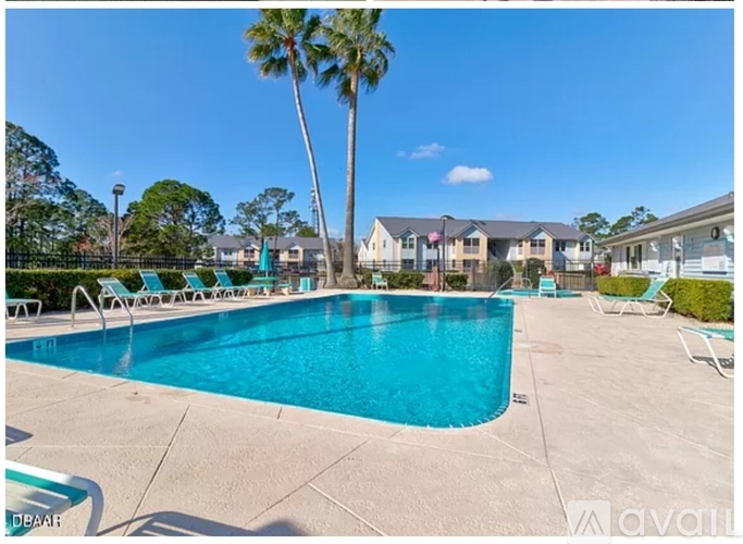 A swimming pool surrounded by lounge chairs and palm trees.