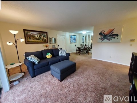 A living room with a blue couch and a painting on the wall.