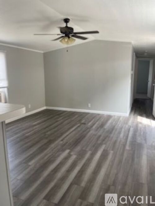 A room with a ceiling fan and wood flooring.