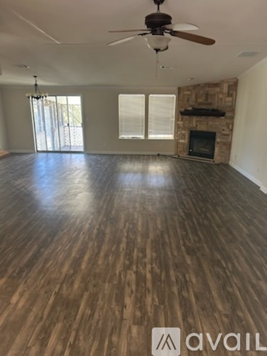 A spacious room with wooden flooring and a ceiling fan.