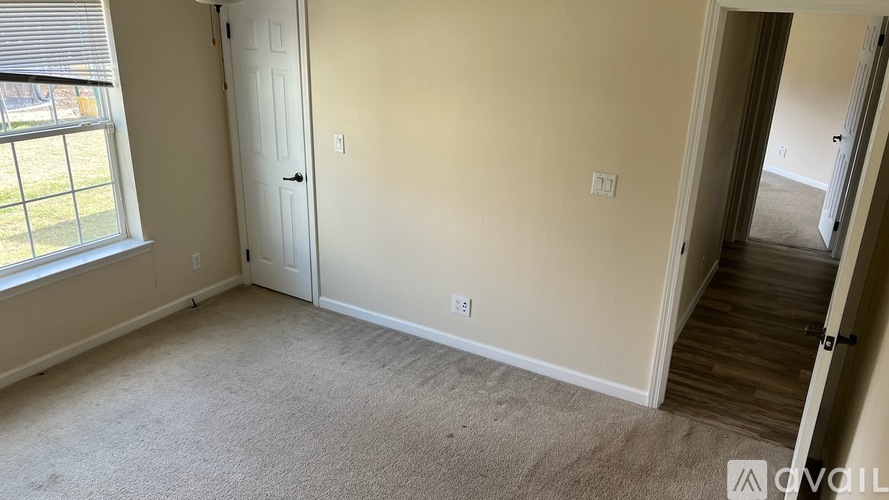 A room with a carpeted floor, a door, and a window with blinds.