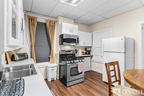 A kitchen with a white fridge, white cabinets, and a white sink.