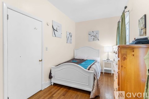 A bedroom with a white bed and wooden floors.