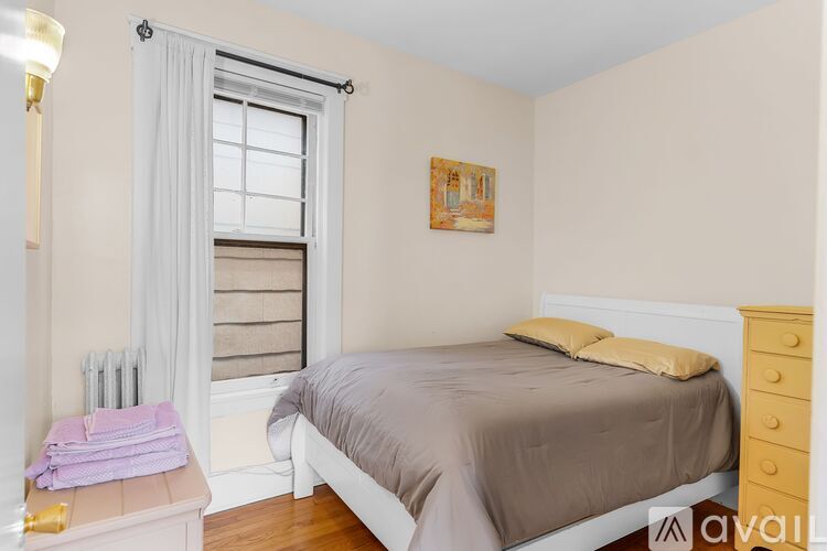 A bedroom with a bed, nightstand, and window.