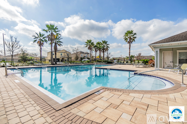 A pool surrounded by palm trees and a house in the background.