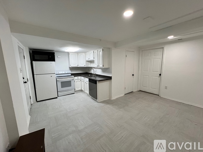 A spacious kitchen with white cabinets and appliances, a dining area with a table and chairs, and a living area with a couch and a television.
