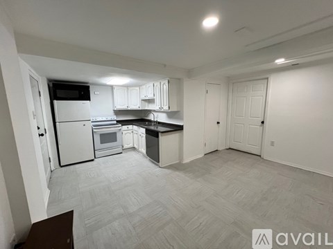 A spacious kitchen with white cabinets and appliances, a dining area with a table and chairs, and a living area with a couch and a television.
