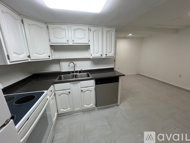 A kitchen with white cabinets and black countertops.
