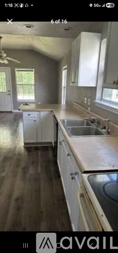 A kitchen with white cabinets and a wooden floor.