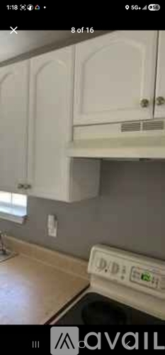 A white cabinet with a black handle is mounted on a wall.