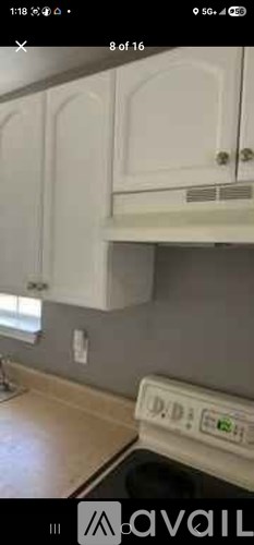 A white cabinet with a black handle is mounted on a wall.