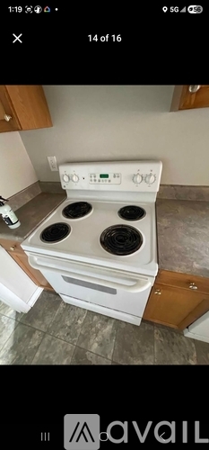 A white stove top oven with four burners is in a kitchen.