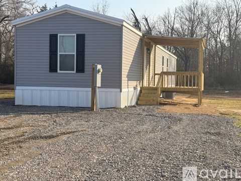 A grey house with a wooden deck attached to it.