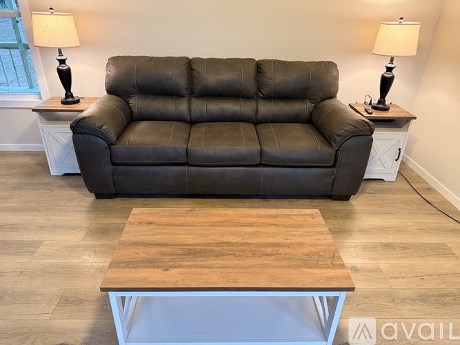A black leather sofa with a wooden table in front of it.
