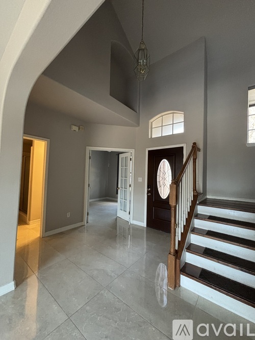 A spacious interior of a house with a staircase and a chandelier.