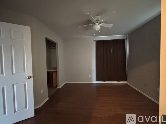 A room with a white door and a ceiling fan.