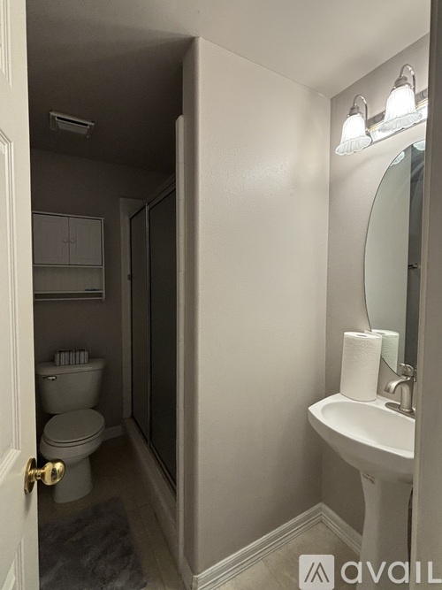 A bathroom with a toilet, sink, and mirror.