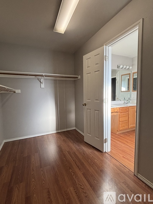 A room with wooden floors and a white door leading to another room.