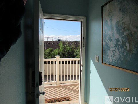 A view from a doorway looking out to a deck with a white fence and a building in the distance.