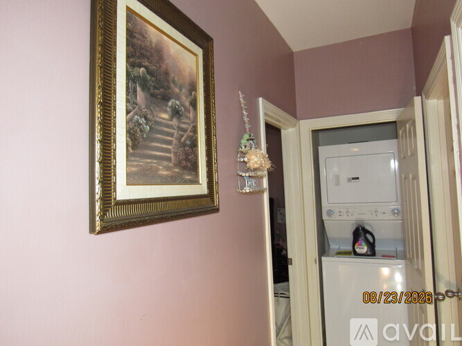 A painting hangs on a wall above a white refrigerator.