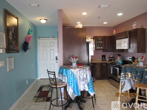 A kitchen with a table set for two and a blue wall.