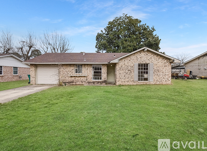 A house with a stone exterior and a large lawn in front.