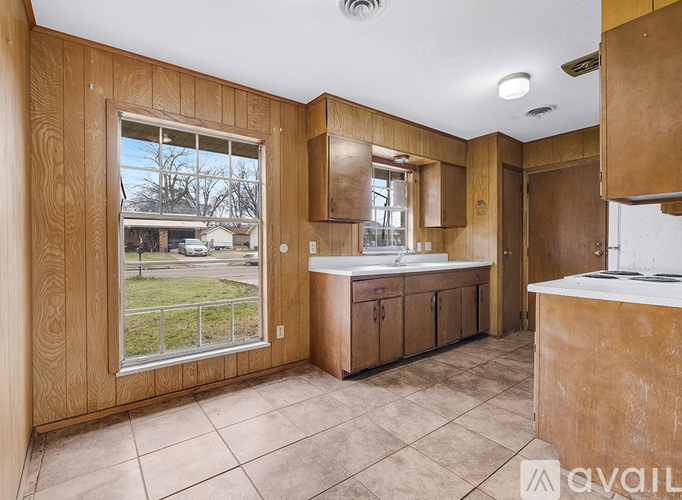 A kitchen with wooden cabinets and a large window overlooking a yard.