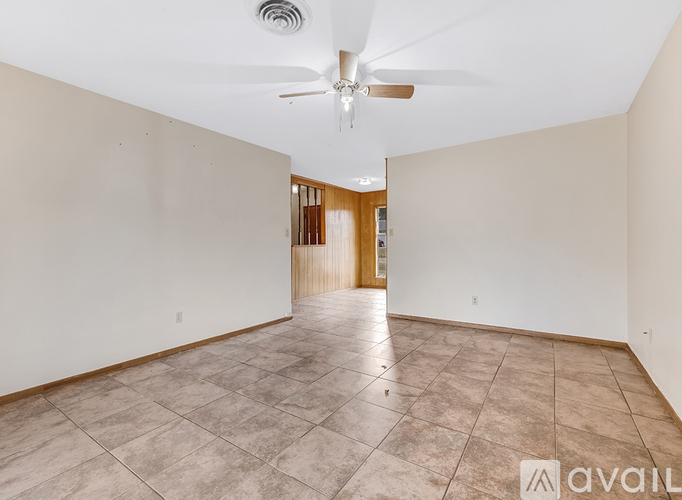 A spacious room with a ceiling fan and tiled flooring.