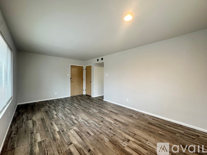 A room with wooden flooring and two doors.