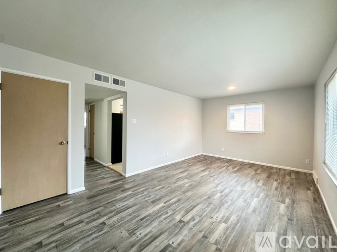A room with wooden flooring and a window on the right side.