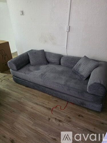 A grey couch with pillows is on a wooden floor in a room.