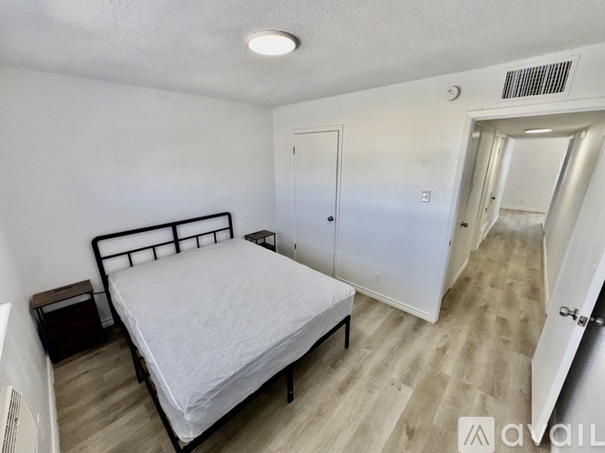 A bedroom with a bed, nightstand, and two doors.
