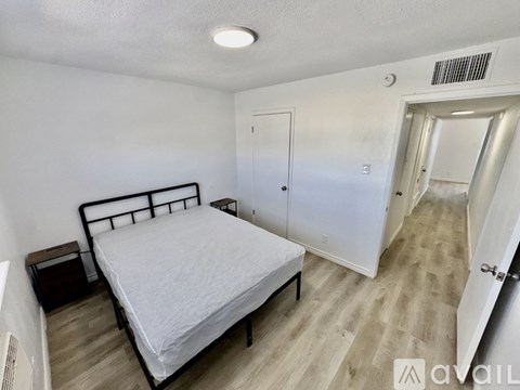 A bedroom with a bed, nightstand, and two doors.