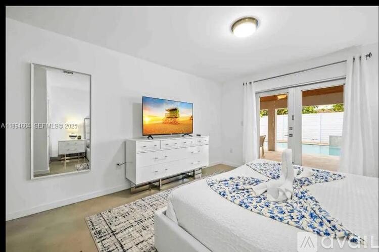 A bedroom with a large bed and a flat screen TV mounted on the wall.