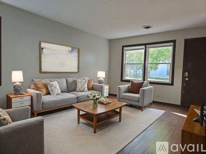A living room with a grey couch, a coffee table, and a painting on the wall.