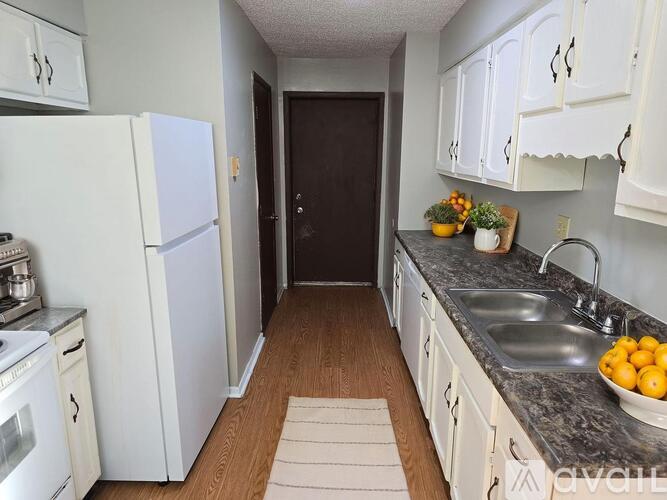 A kitchen with white cabinets and a black door.