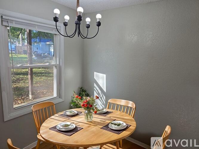 A dining room with a table set for two and a chandelier.