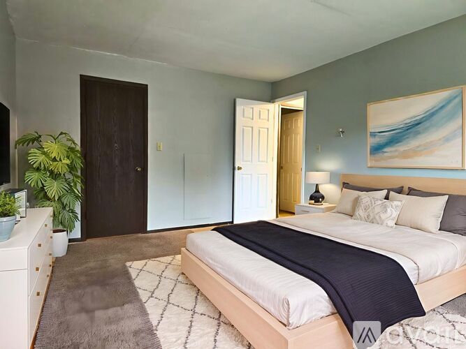 A bedroom with a large bed and a painting on the wall.