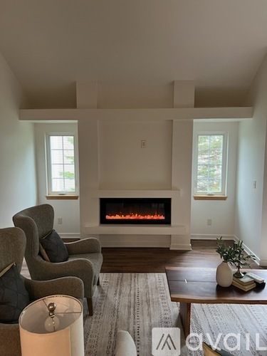 A living room with a fireplace and two chairs.