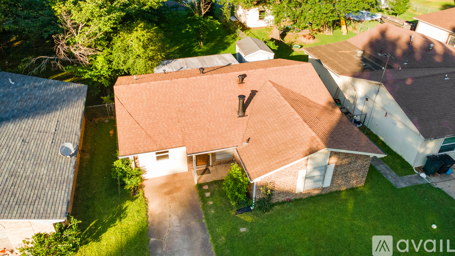 A house with a brown roof and a garage is surrounded by greenery.